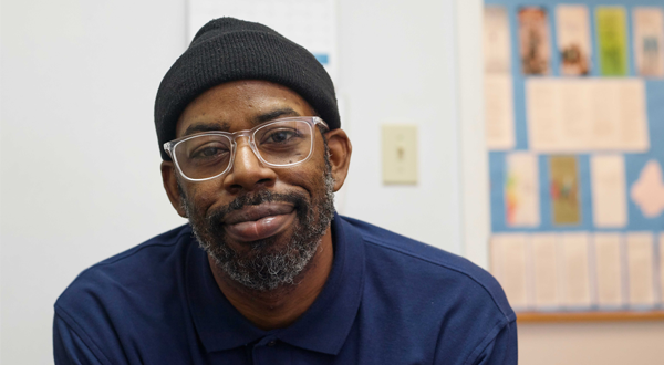 man with glasses and wearing a hat, smiling